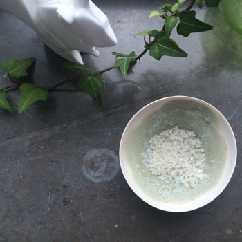 Small porcelain bowl filled with sea salt on a limestone surface