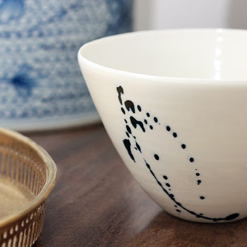 White porcelain bowl with some blue splattering on a wooden surface