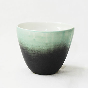 Black and green tea-cup without ears against a white backdrop