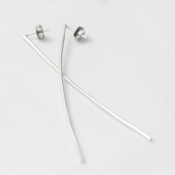 Long and narrow silver earrings laying flat on a white background