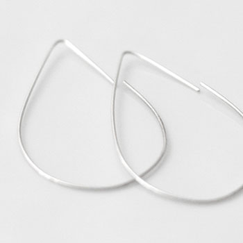 Teardrop shaped silver earrings against a white surface